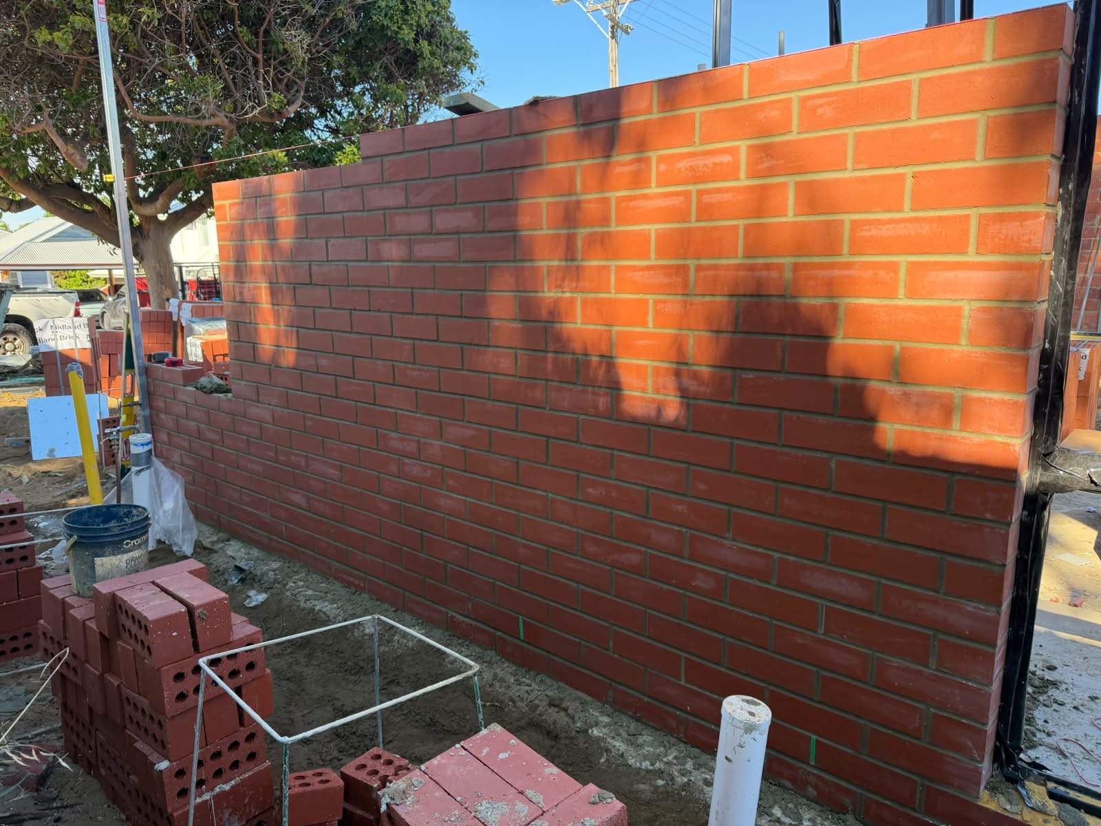 A freshly laid wall of red smooth face bricks on a residential site, before painting